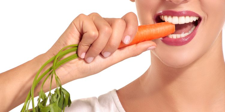 Photo of woman with healthy teeth biting the carrot