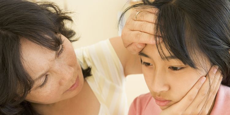 Photo of a mother holding her ill child's forehead