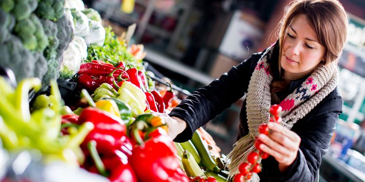 Photo of woman picking vegetable at marketplace