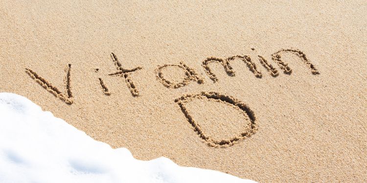 Photo of vitamin D word written on beach sand